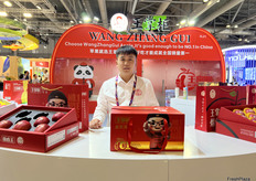 苹果是王掌柜农业的主打产品，公司带来了多款包装礼盒苹果做展示。销售代表王帅在展位前。/ Apples are Wang Zhang Gui Agriculture's main product, and the company showcased a variety of gift-boxed apples. Sales representative Shuai Wang at the booth.