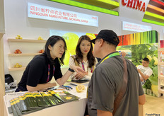 四川省柠点农业有限公司的参展代表（左一，左二）与访客交谈。/ Exhibition representatives from Sichuan Ningdian Agriculture Co., Ltd. (first and second from left) are talking with visitors.