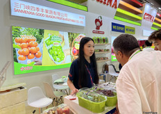 三门峡四季丰果蔬有i西安公司的参展代表（左一）与到访展位的访客交谈。/ Exhibition representative from Sanmenxia Good Season Fruit&Vegetable Co., Ltd. (first from left) is talking with visitors at the booth.