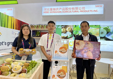 河北雄瀚农产品股份有限公司的负责人李先生（右一）及参展代表李茜茜（左一）展示公司样品。该公司在河北有自有基地，出口皇冠梨，鸭梨等多品种鲜梨。/ Mr. Li (first from right), head of Hebei Xionghan Agricultural Products Inc., and Qianqian Li (first from left), the representative from the company at the exhibition, are displaying company samples. The company operates its own production base in Hebei and exports a variety of fresh pear varieties, including Crown Pears and Ya Pears.
