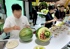 水果雕花表演者在百果园展位用西瓜进行雕花。/ Fruit carving performers are carving flowers out of watermelons at the Pagoda booth.