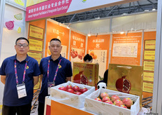 来自简阳市丰禾园农业专业合作社的赵经理（左一）和同事在展位前。此次参展，公司带来了包括软籽石榴，尤克力柠檬柠檬，沃柑在内的多品类多种四川农产品做展示。/ Manager Zhao (first from left) and his colleague from Jianyang Fengheyuan Mandarin&Pomegranate Export Orchard at their booth. The company showcased a variety of Sichuan agricultural products, including soft-seeded pomegranate, Eureka lemon, and Wogan.