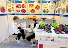 济宁尚卓食品有限公司的参展代表（右一）正在与访客进行交谈。/ An exhibition representative from Jining Shangzhuo Food Co., Ltd. (first from the right) is talking with a visitor.