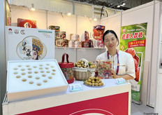 晚熟龙眼是泸县中荔农产品商贸有限责任公司的主营产品。参展代表在展位前展示包装精美的龙眼产品。/ Late longan is the main product of Luxian Zhongli Agricultural Products Trading Co., Ltd. The company is displaying well packaged longan products at their booth.