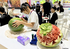 雕花表演者在鑫荣懋展台上，用西瓜做雕花。/ A carving performer is carving patterns out of watermelon at the Joy Wing Mau booth.