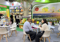 四川维记农业集团有限公司的展位上，参展代表正在与到访客商交谈。/ At the booth of Sichuan Wikee Group Co., Ltd., exhibition representatives are talking with visiting merchants.