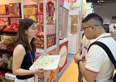 访客正在厦门市赋果鲜供应链的展位试吃果品。/ Visitors are tasting fruits at the booth of Xiamen Fuguoxian Supply Chain.