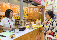 内蒙古美壹甜粮油食品股份有限责任公司的参展代表正在向访客介绍公司的玉米产品。/ An exhibition representative from Inner Mongolia Meiyi Sweet Grain and Oil Food Co., Ltd. is introducing the company's corn products to visitors.