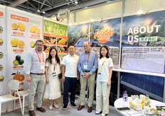 四川省鑫柠乐果业有限公司的参展代表与到访客商在展位进行合照。/ Exhibitors from Sichuan Xinningle Fruit Industry Co., Ltd. are taking photos with visitors at the booth.