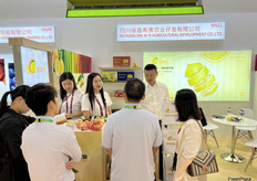 四川省鑫希夷农业开发有限公司的参展代表与到访展位的访客交谈。/ Exhibition representatives from Sichuan Xin Xi Yi Agricultural Development Co., Ltd. are talking with visitors at the booth.