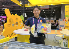 来自周榴莲的参展代表黄先生正在展示公司的特色产品薄皮榴莲。/ Mr. Huang, the exhibitor representative from Zhou Durian, is showcasing the company's specialty product, thin-skinned durian.