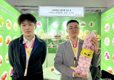 Alan (1st from the left) and Zhe Sun at Jining New Silk Road Food Co., Ltd. The company exports a variety of agricultural products, including ginger, garlic, carrots, and onion. / Alan（左一）和 Zhe Sun 在济宁新丝路食品有限公司展位。该公司出口各种农产品，包括生姜、大蒜、胡萝卜和洋葱。